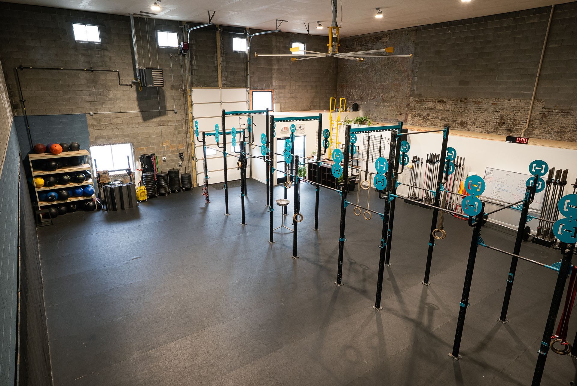 Gym interior in Asheville, NC with exercise equipment and dark floor. Blue and yellow accents on equipment.
