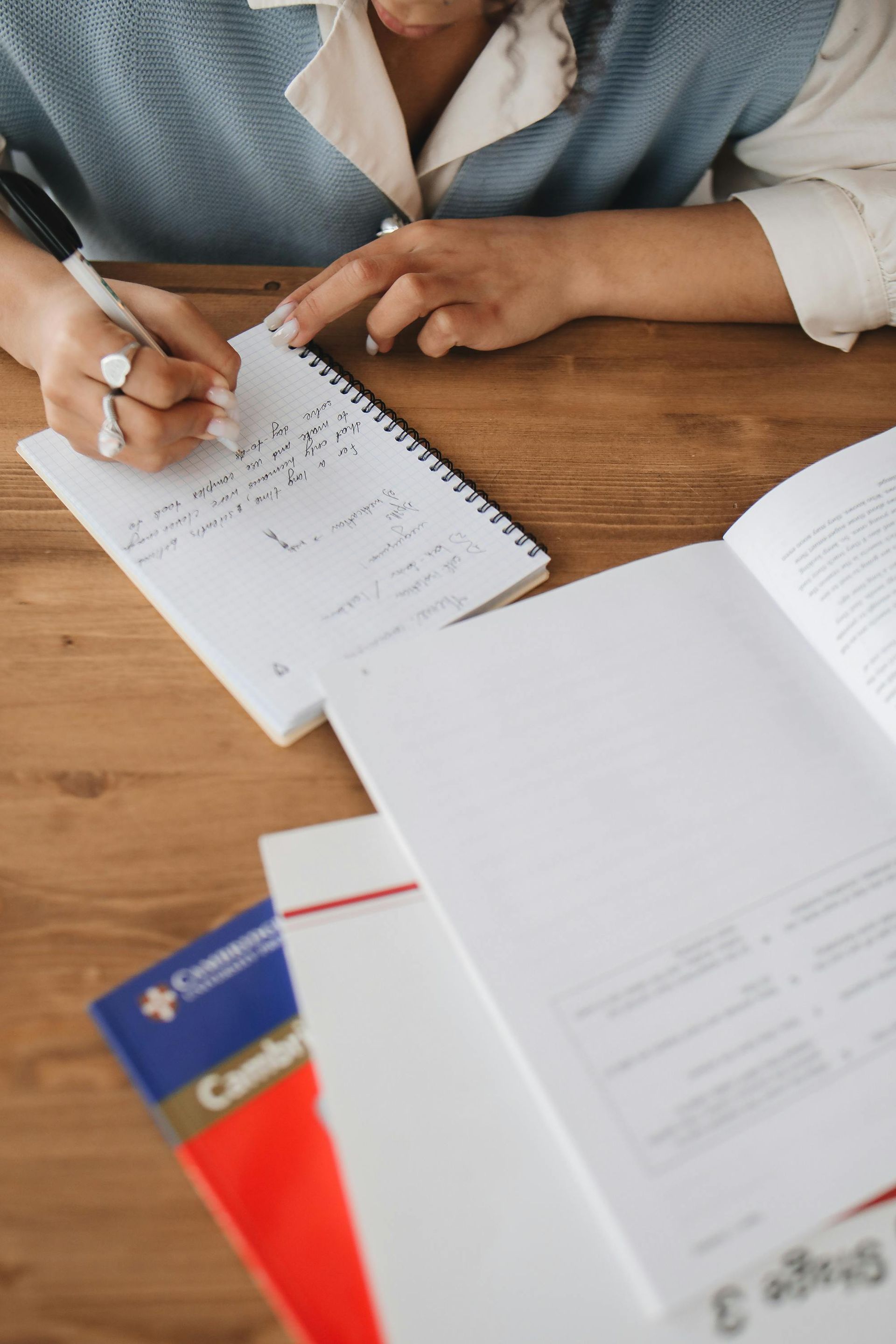 A Woman Is Sitting At A Table Writing In A Notebook — The Molecule Mentor in Lorn, NSW