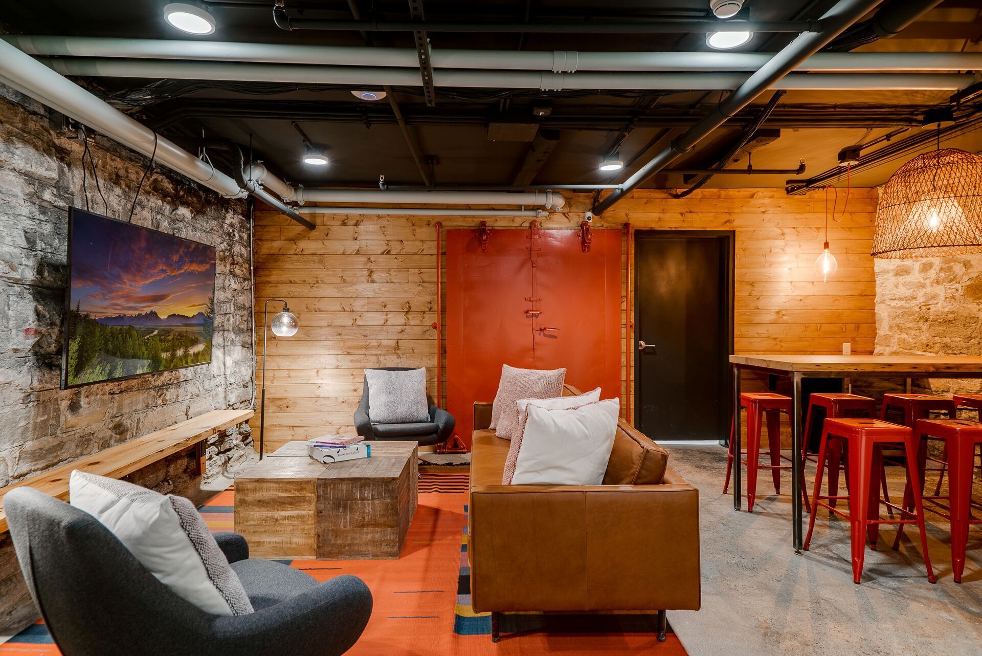 Cozy lounge with exposed brick and wood, featuring seating, table, and a bar area with red stools at Commission House, offers apartments in Lowertown St Paul, MN.