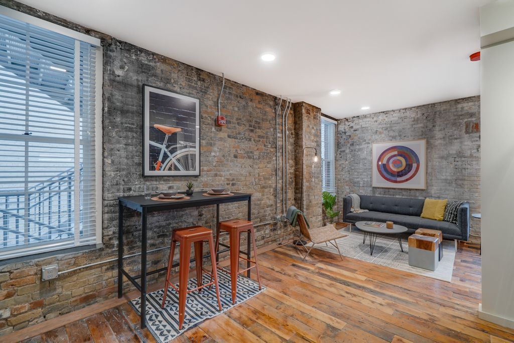 Living room with brick walls, high table with stools, sofa, and round art.