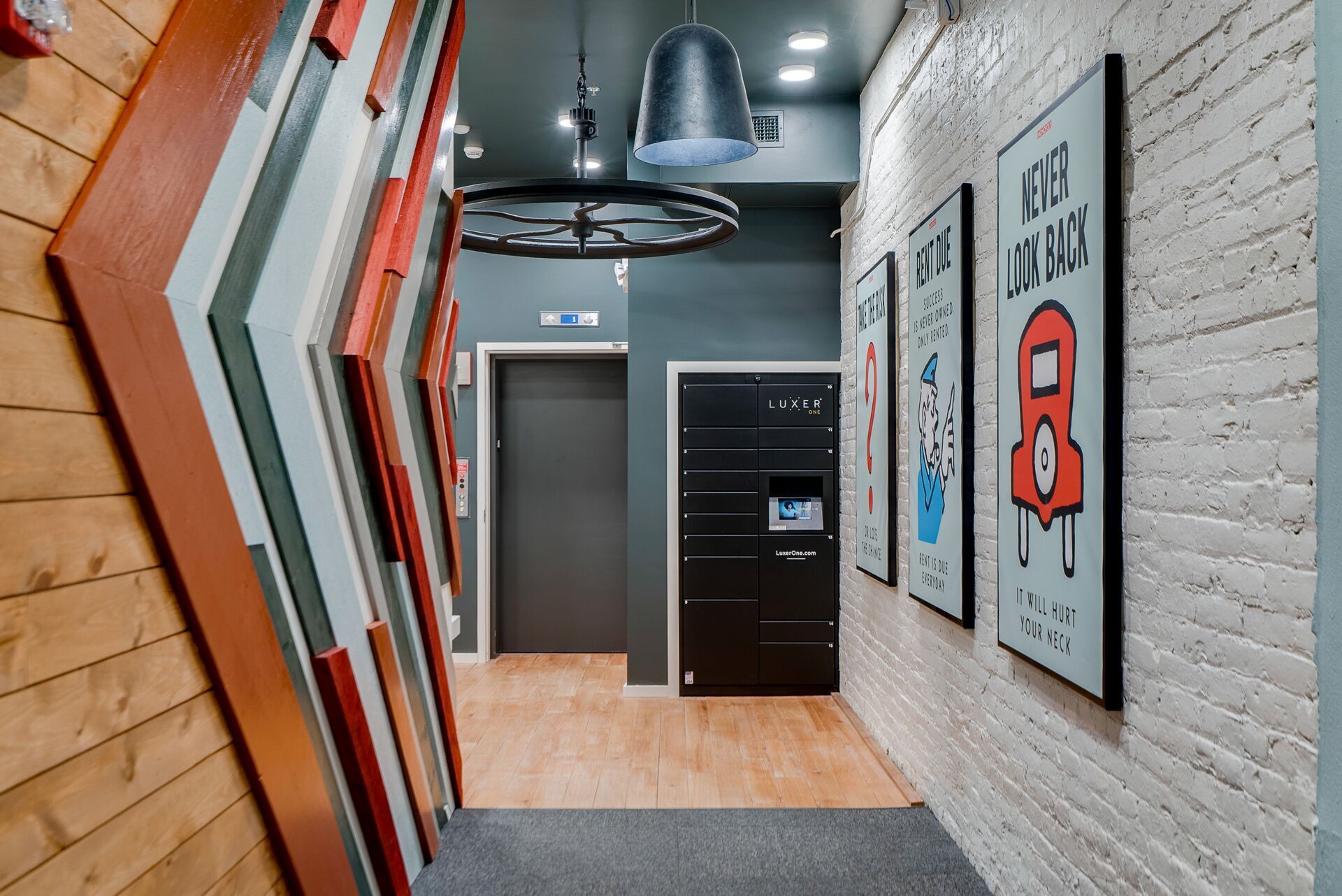 Hallway with white brick wall, wooden chevron wall, and posters at Commission House, offers apartments in Lowertown St Paul, MN.