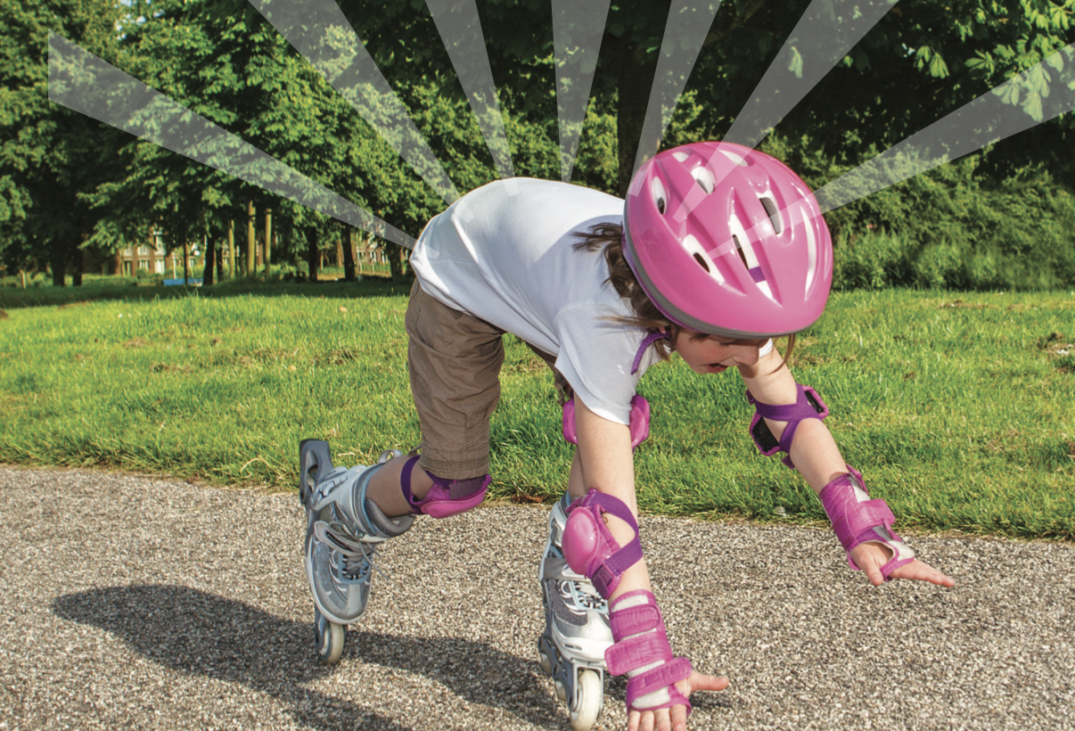 A child wearing a pink helmet and protective gear falls on roller skates on a pathway.