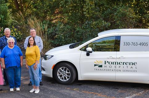 Group of five people posing by a white Pomerene Hospital van. The van has the phone number 330-763-4905 on the side.