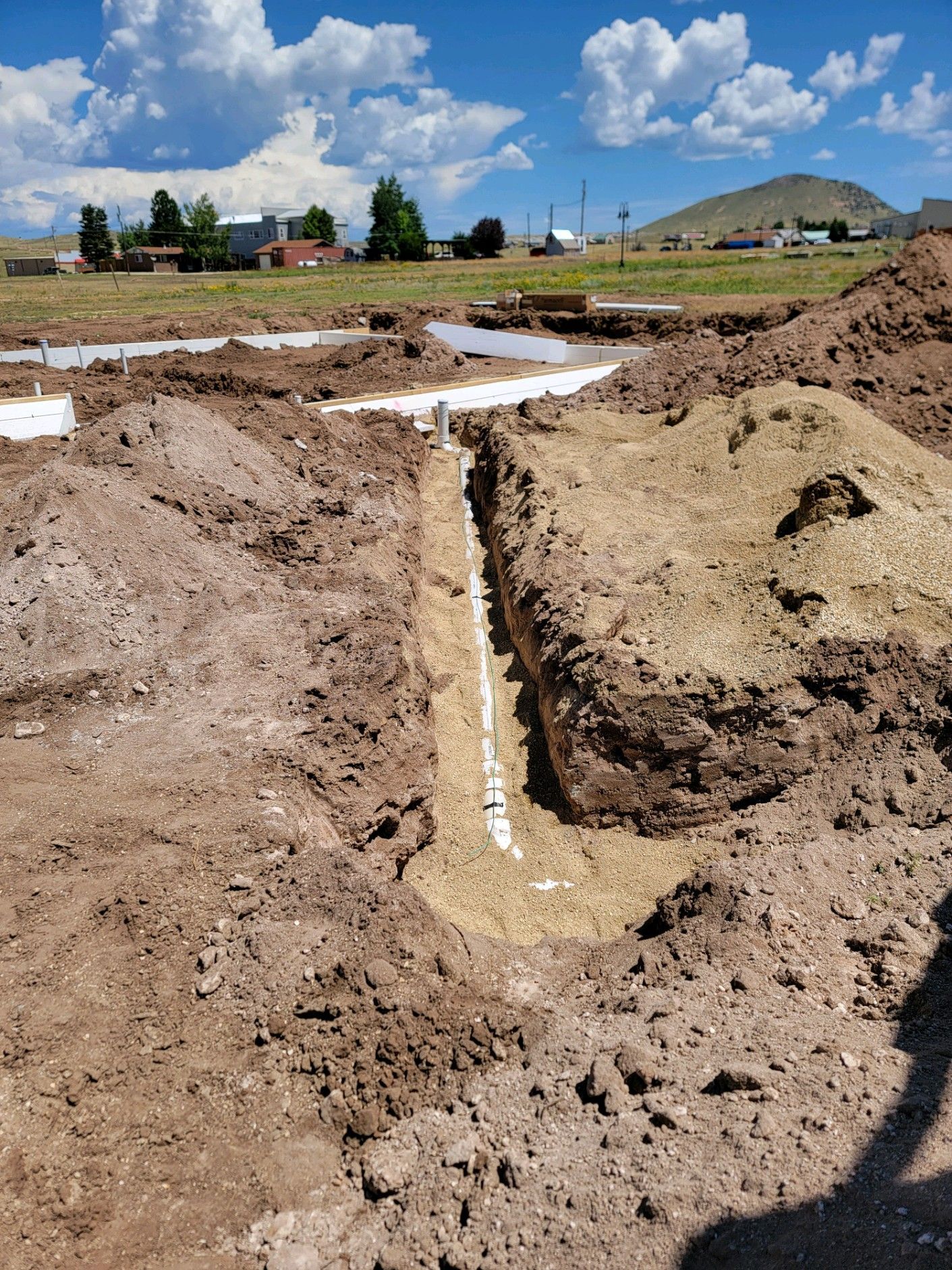 A dirt field with a drain in the middle of it.