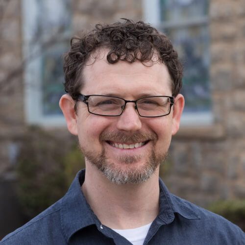 A man with glasses and a beard is smiling for the camera.