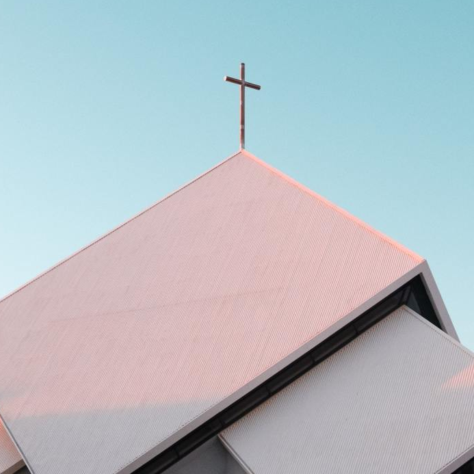 A church with a cross on top of it against a blue sky.