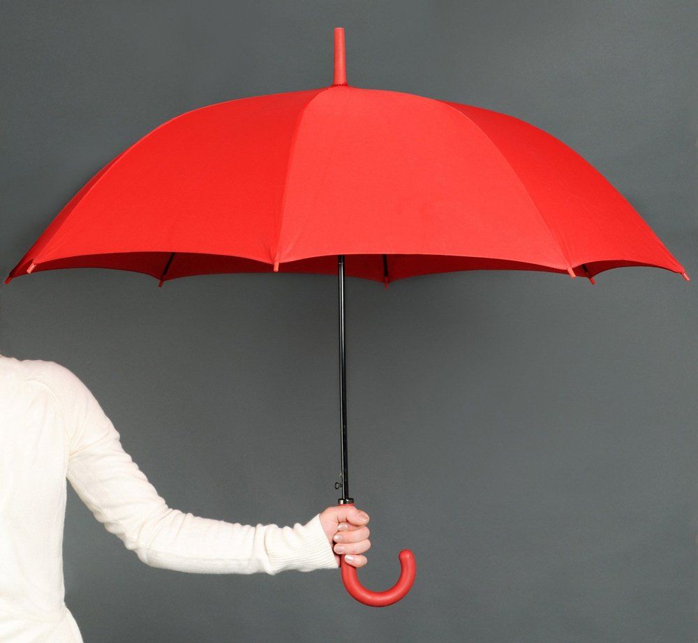A woman in a white shirt is holding a red umbrella
