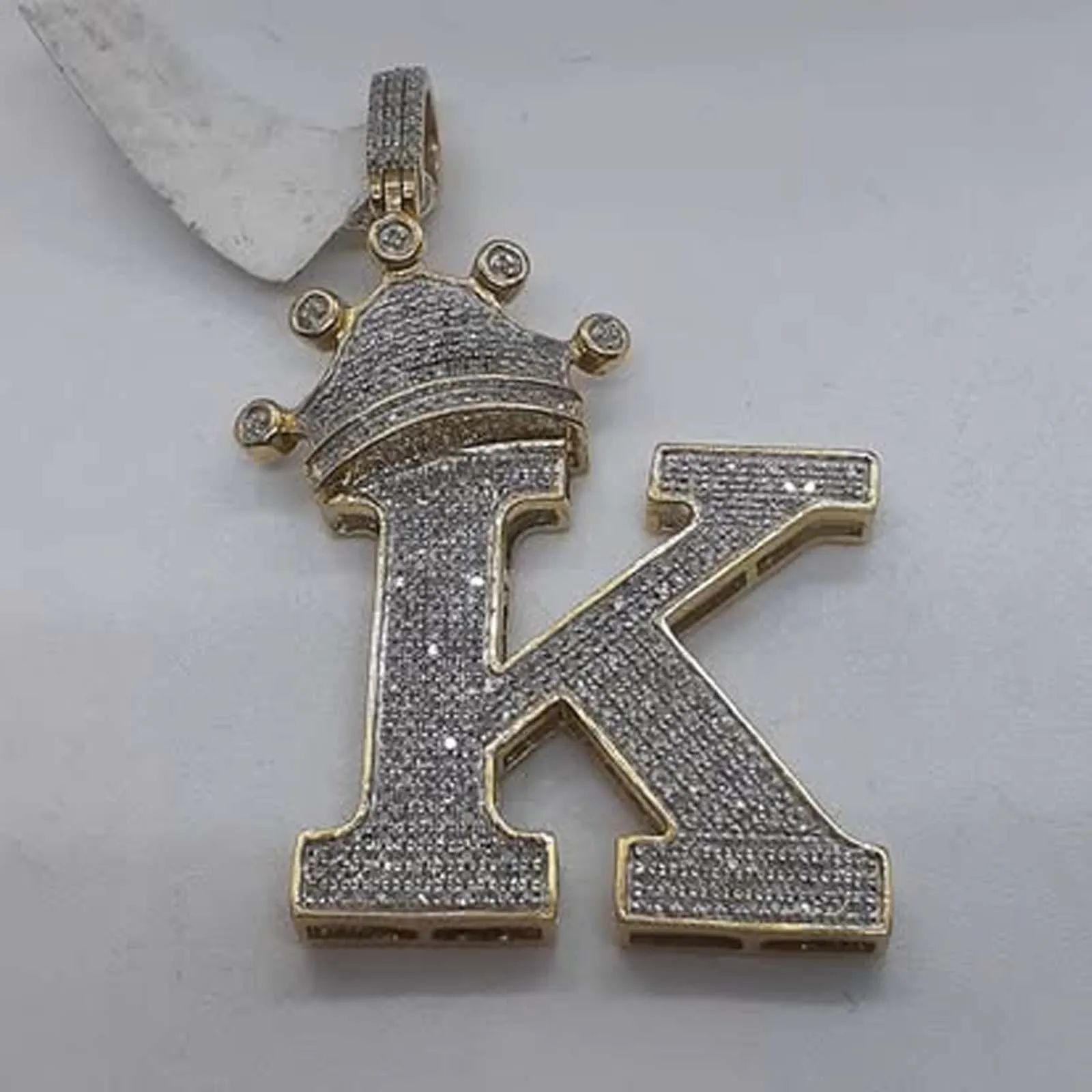 A gold letter k pendant with a crown on top