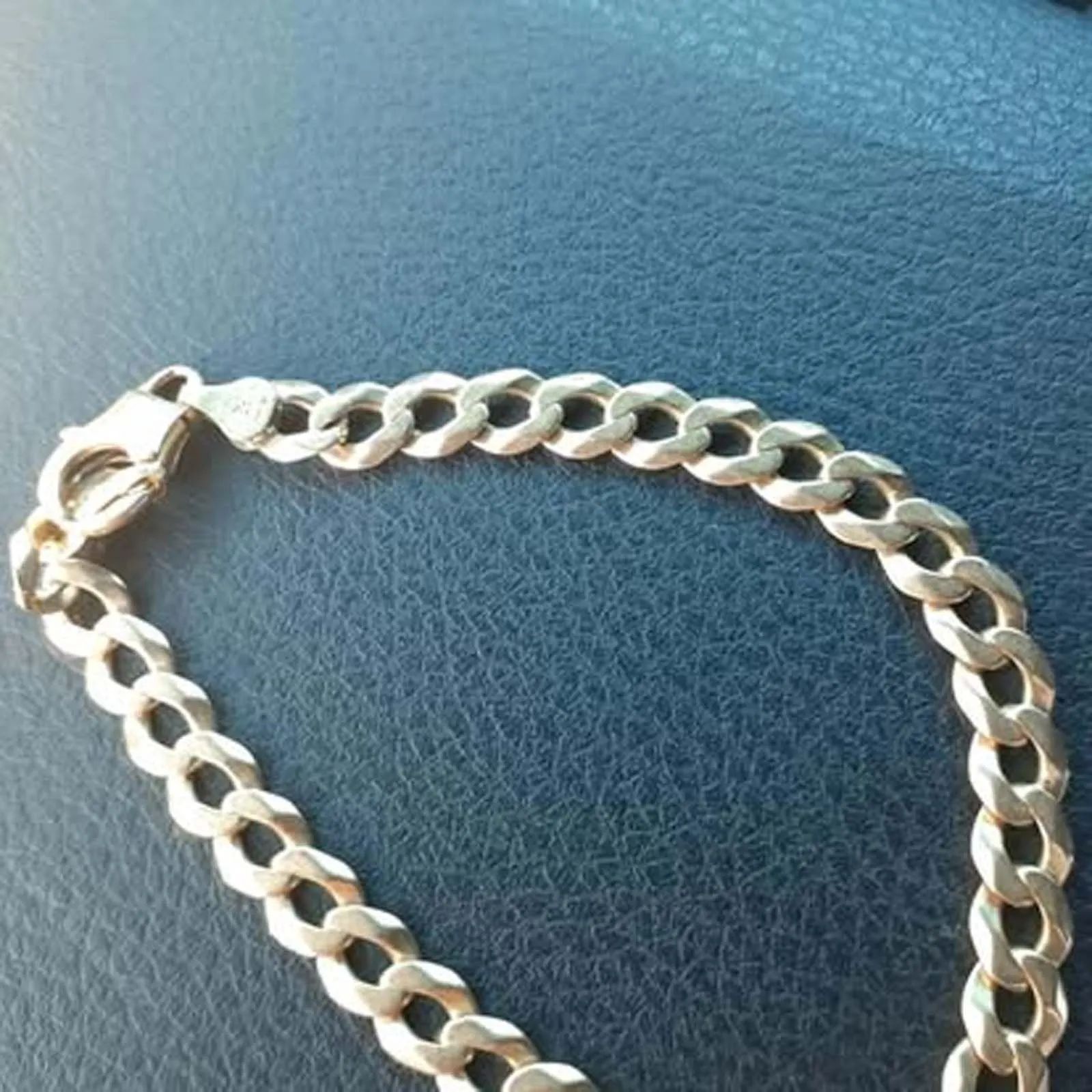 A close up of a gold chain bracelet on a leather surface