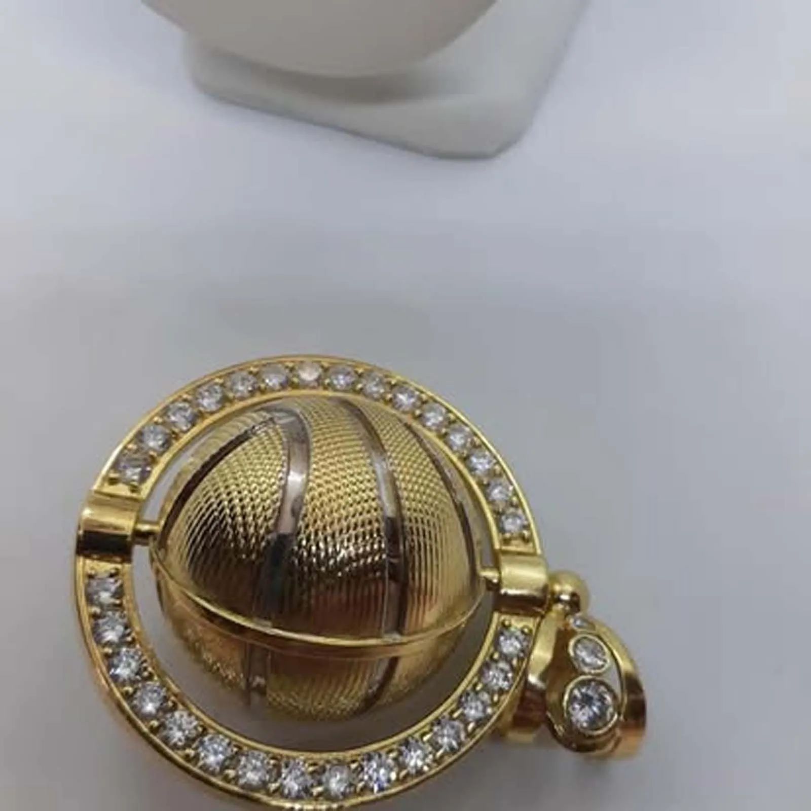 A gold pendant in the shape of a basketball surrounded by diamonds