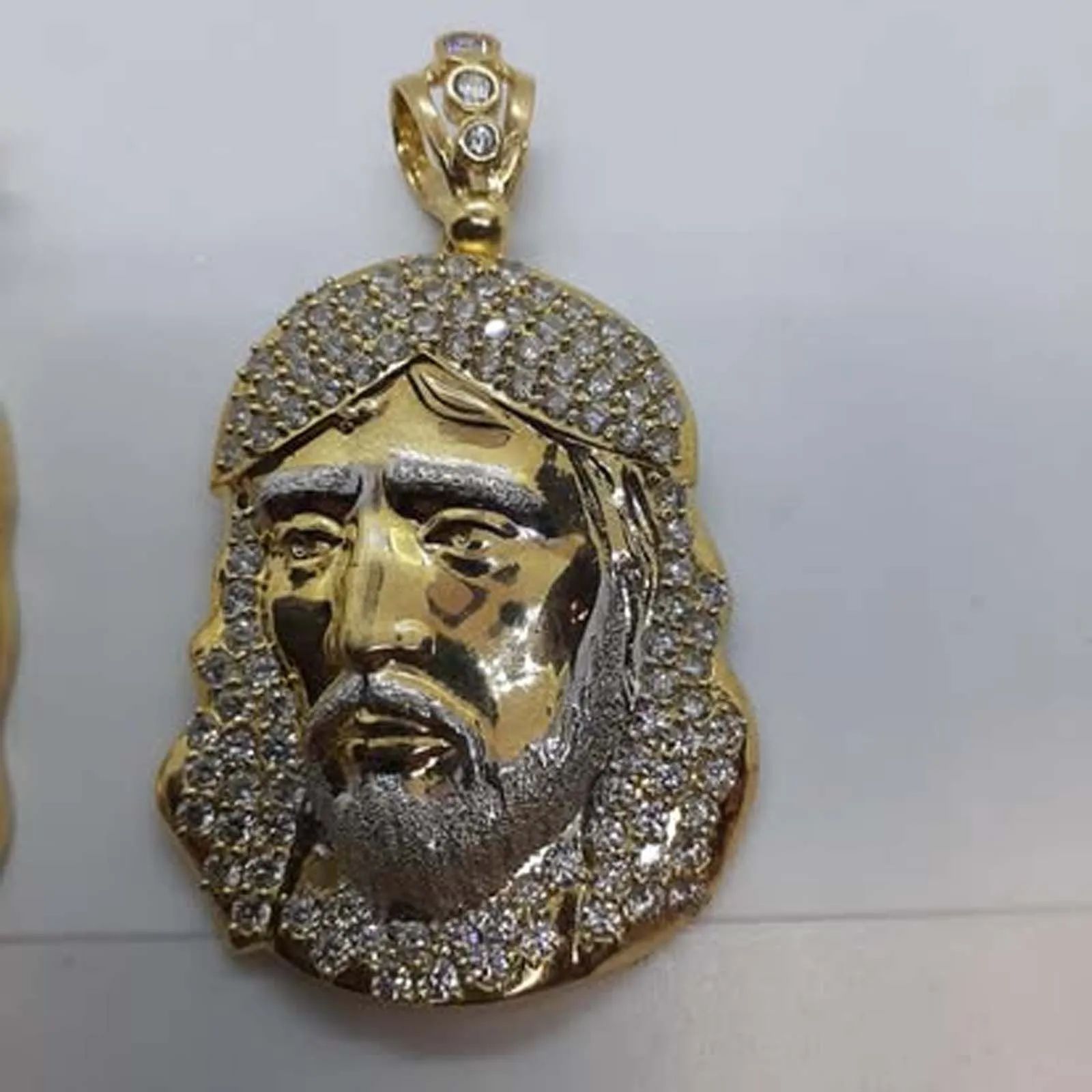 A gold pendant of jesus with a beard and crown of thorns