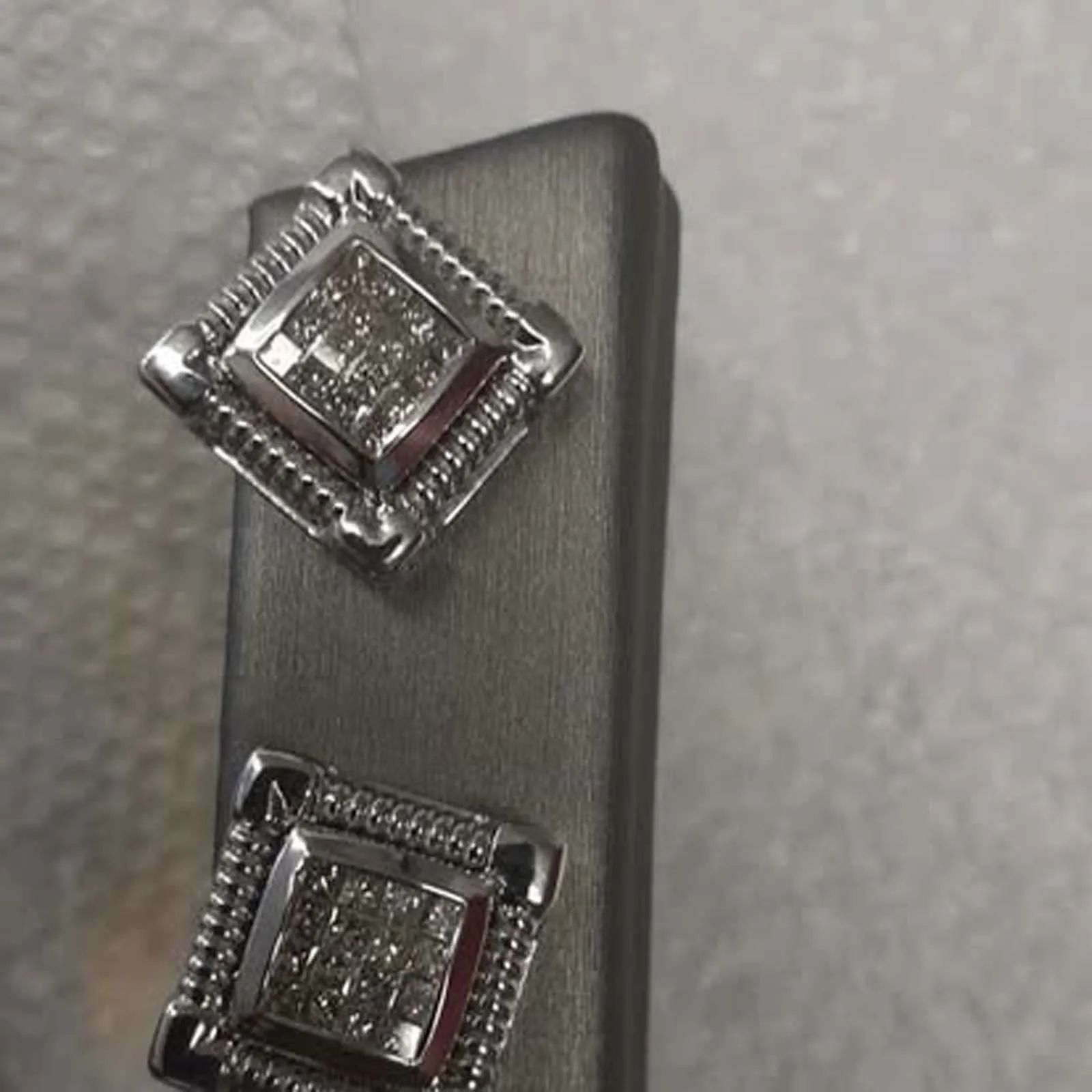 A pair of diamond stud earrings are sitting on top of a black box.