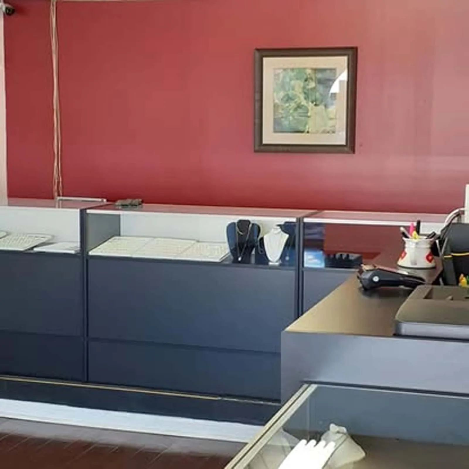 A jewelry store with a red wall and a picture on the wall above the counter.