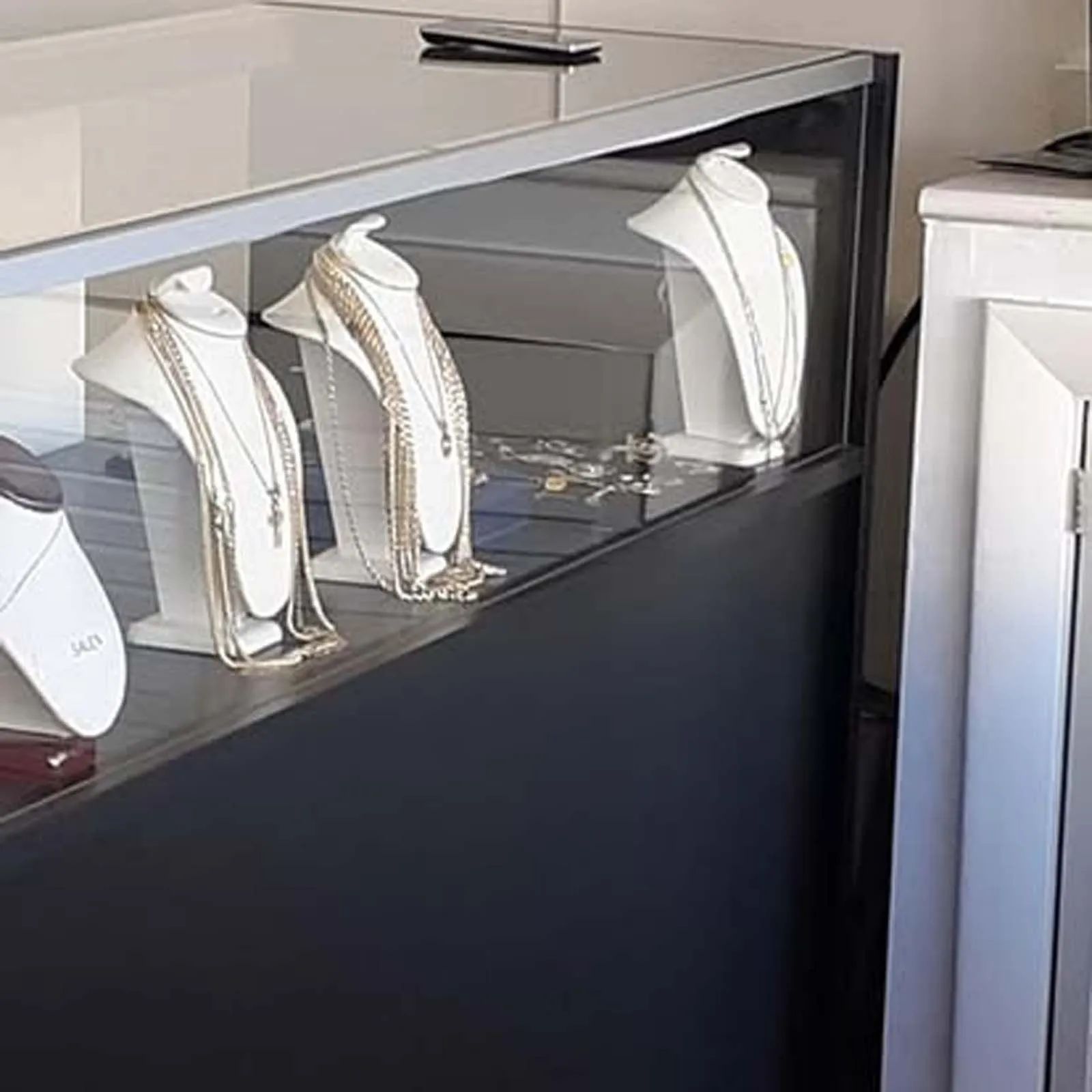 A display case filled with necklaces and bracelets on mannequins.