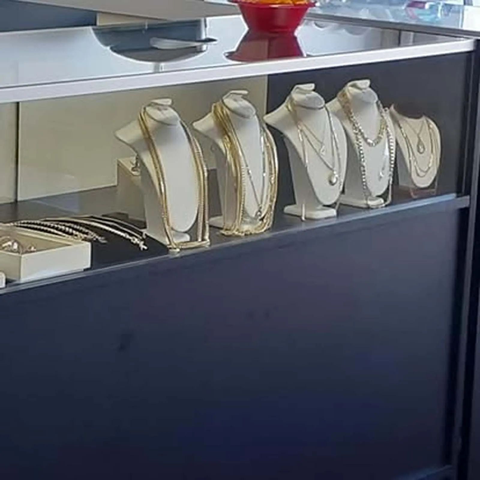 A display case filled with necklaces and bracelets on mannequins.