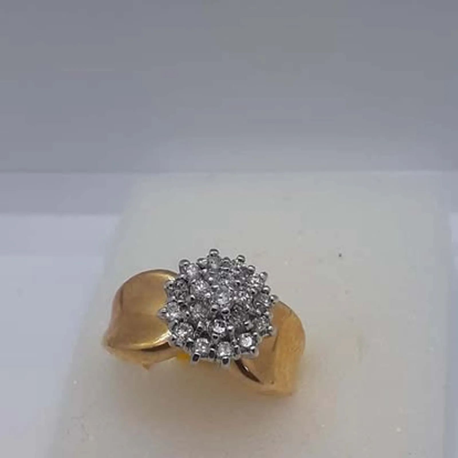 A gold ring with diamonds in a box on a table.
