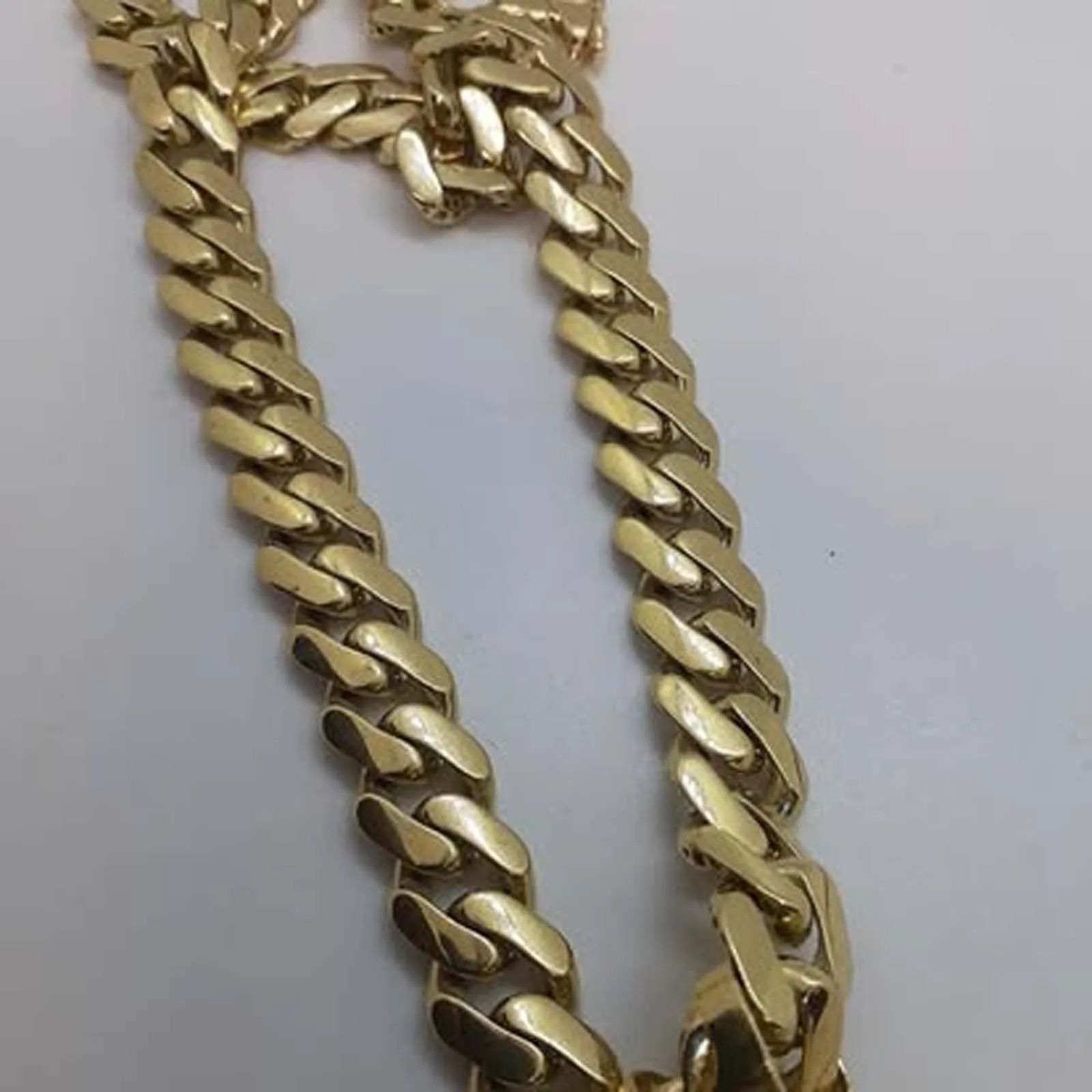 A close up of a gold chain on a white surface