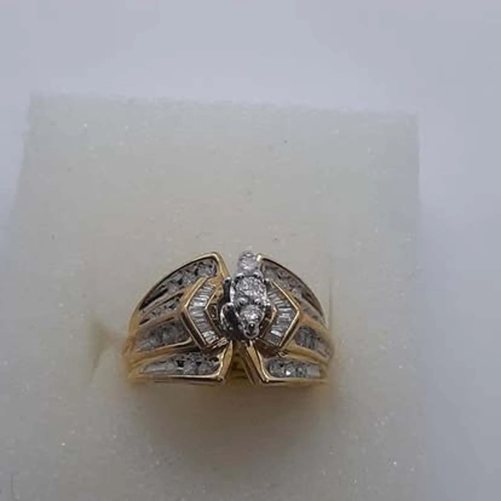 A gold ring with a diamond in the center is sitting on a white surface.