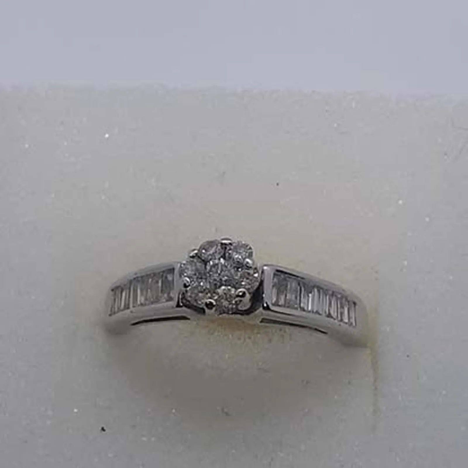 A diamond ring is sitting on a white surface.