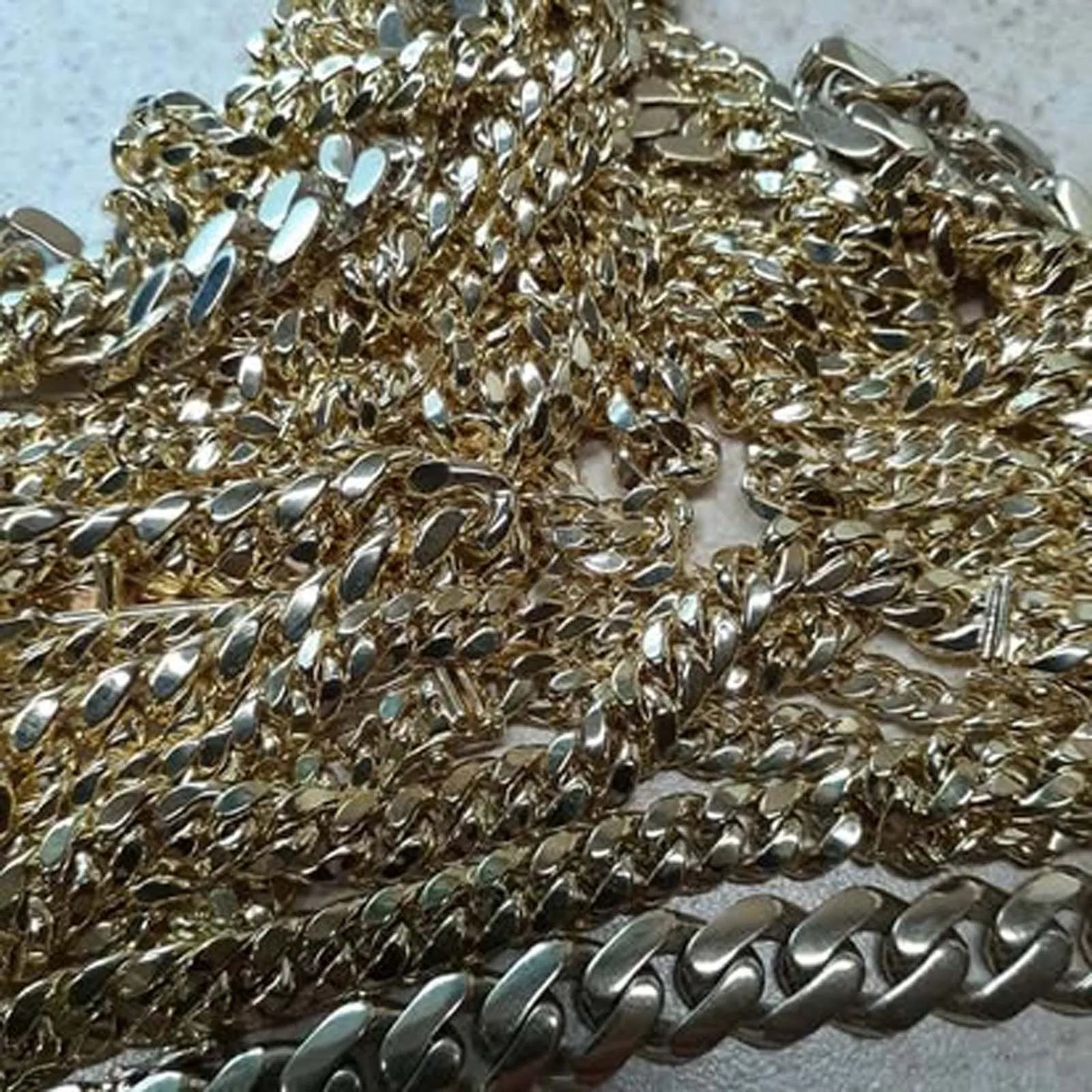 A bunch of gold chains are laying on a table.