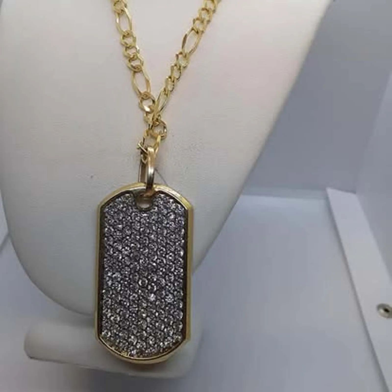 A gold necklace with a dog tag with diamonds on it