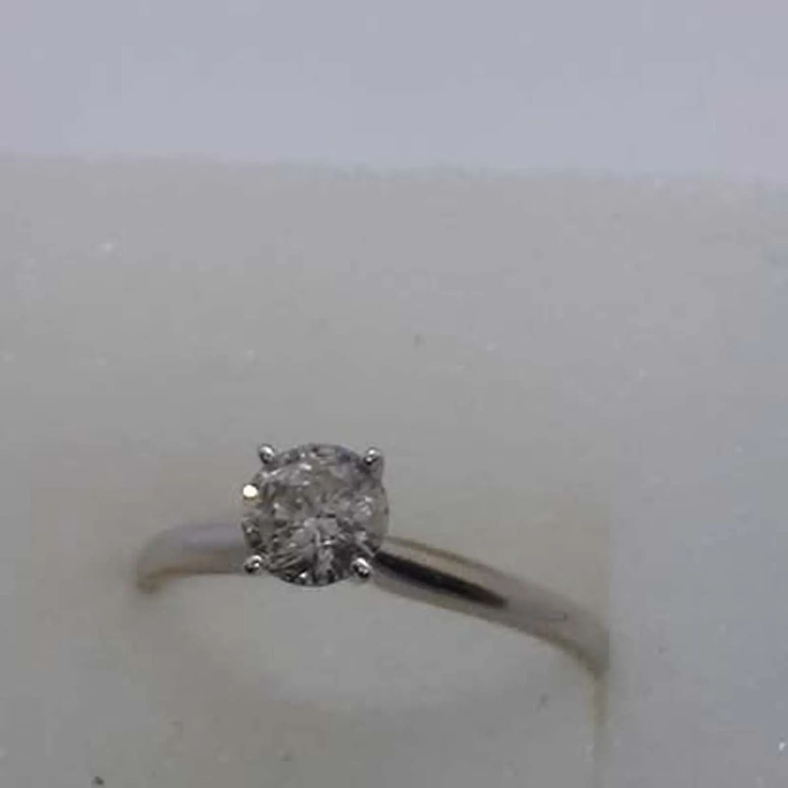 A close up of a diamond ring on a white surface.