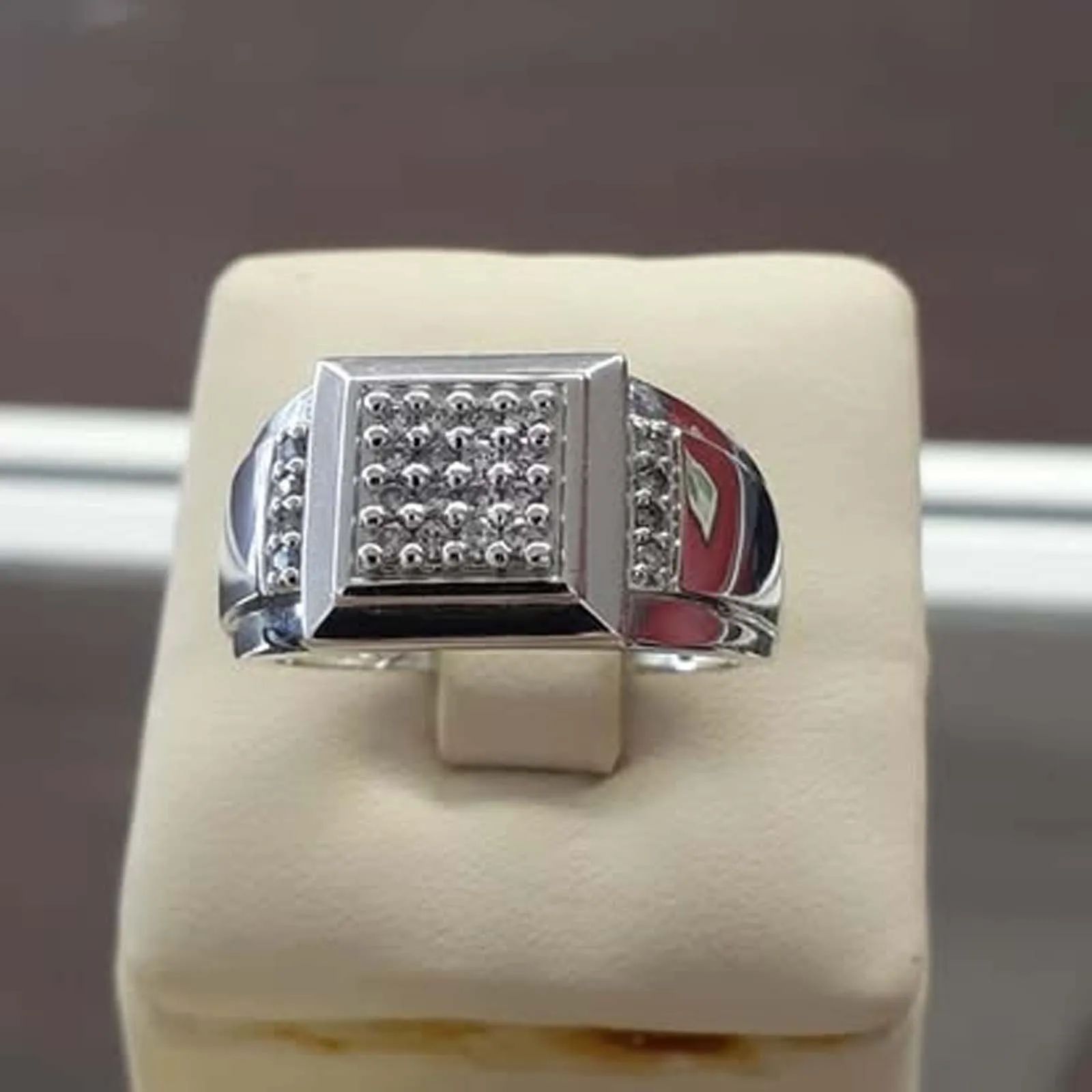 A silver ring is sitting on top of a white cushion.