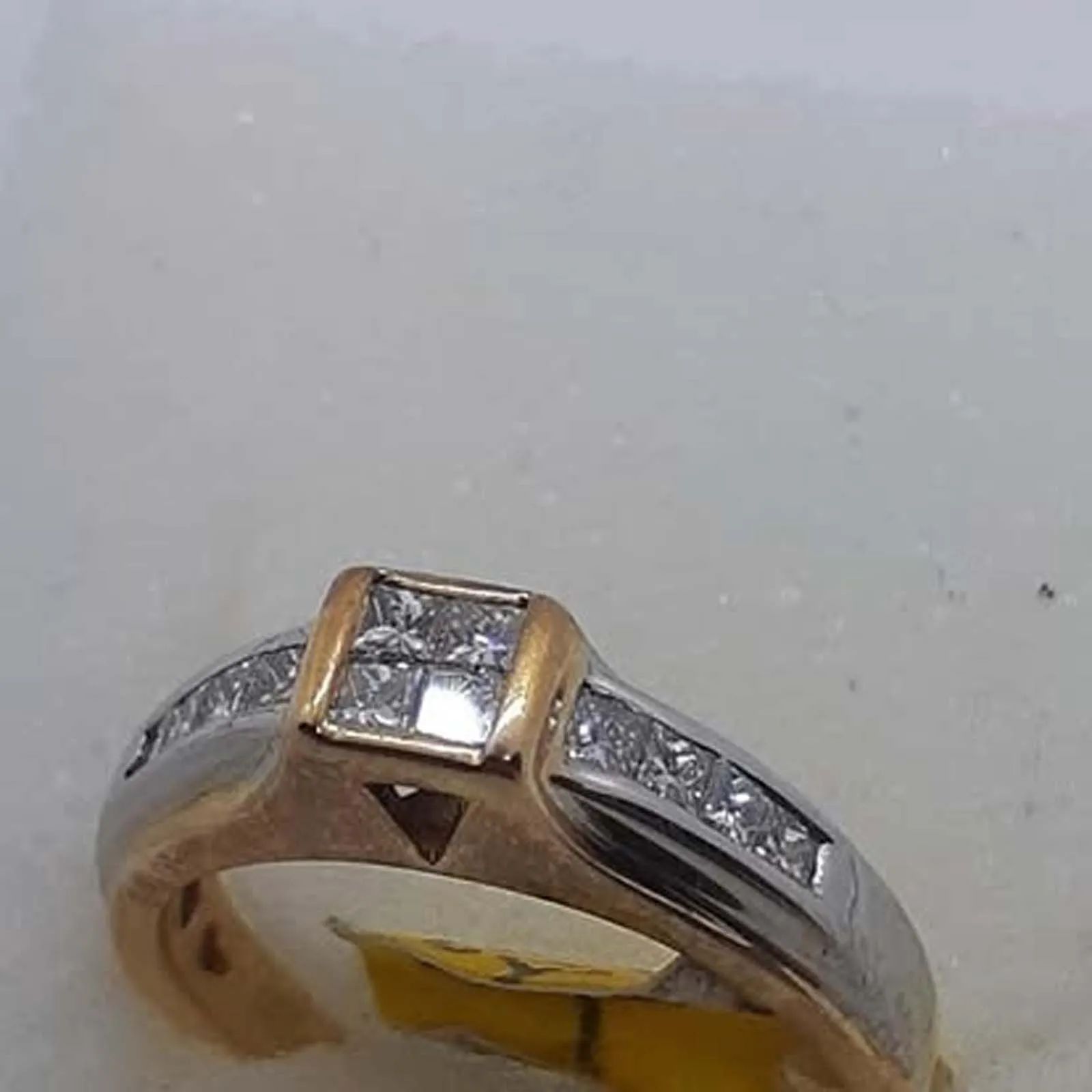 A close up of a diamond ring on a white surface.