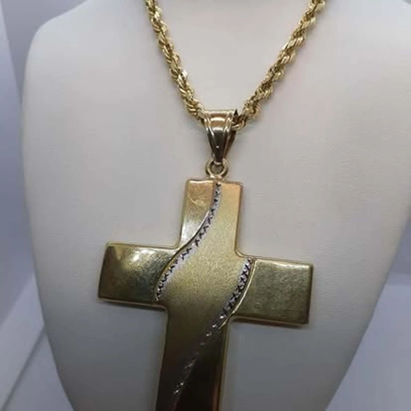 A gold cross necklace is on a mannequin.