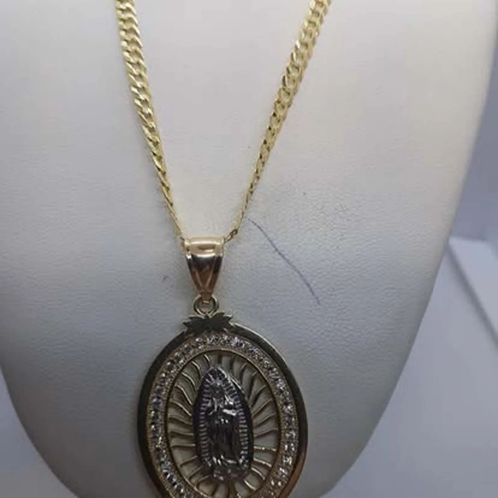 A gold necklace with a pendant of the virgin mary