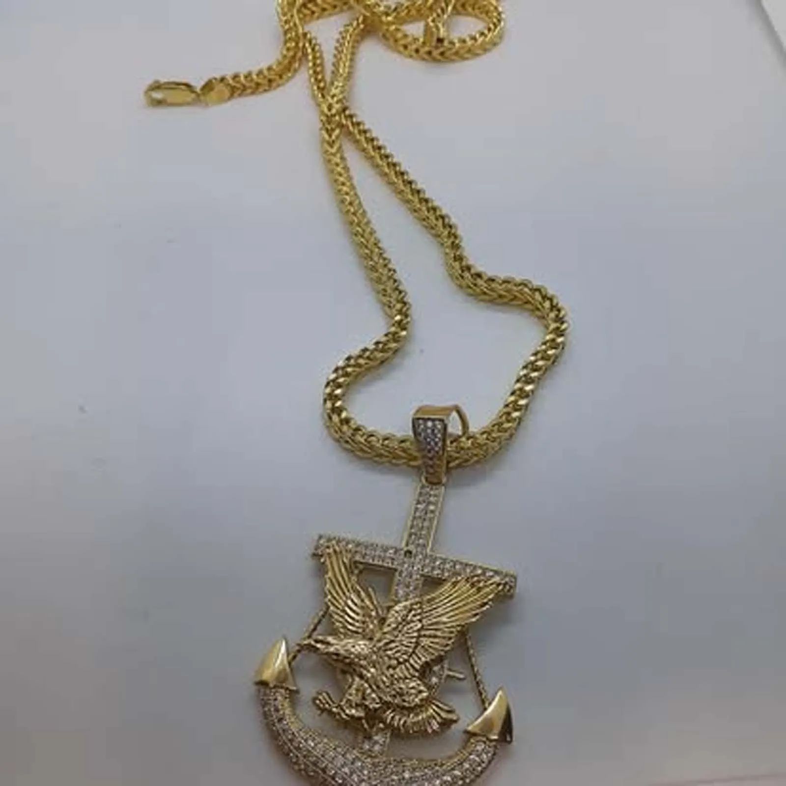 A gold necklace with an anchor with an eagle on it