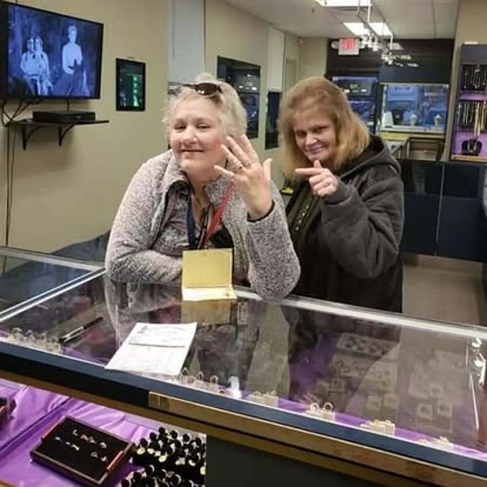 Two women are sitting at a counter in a jewelry store.