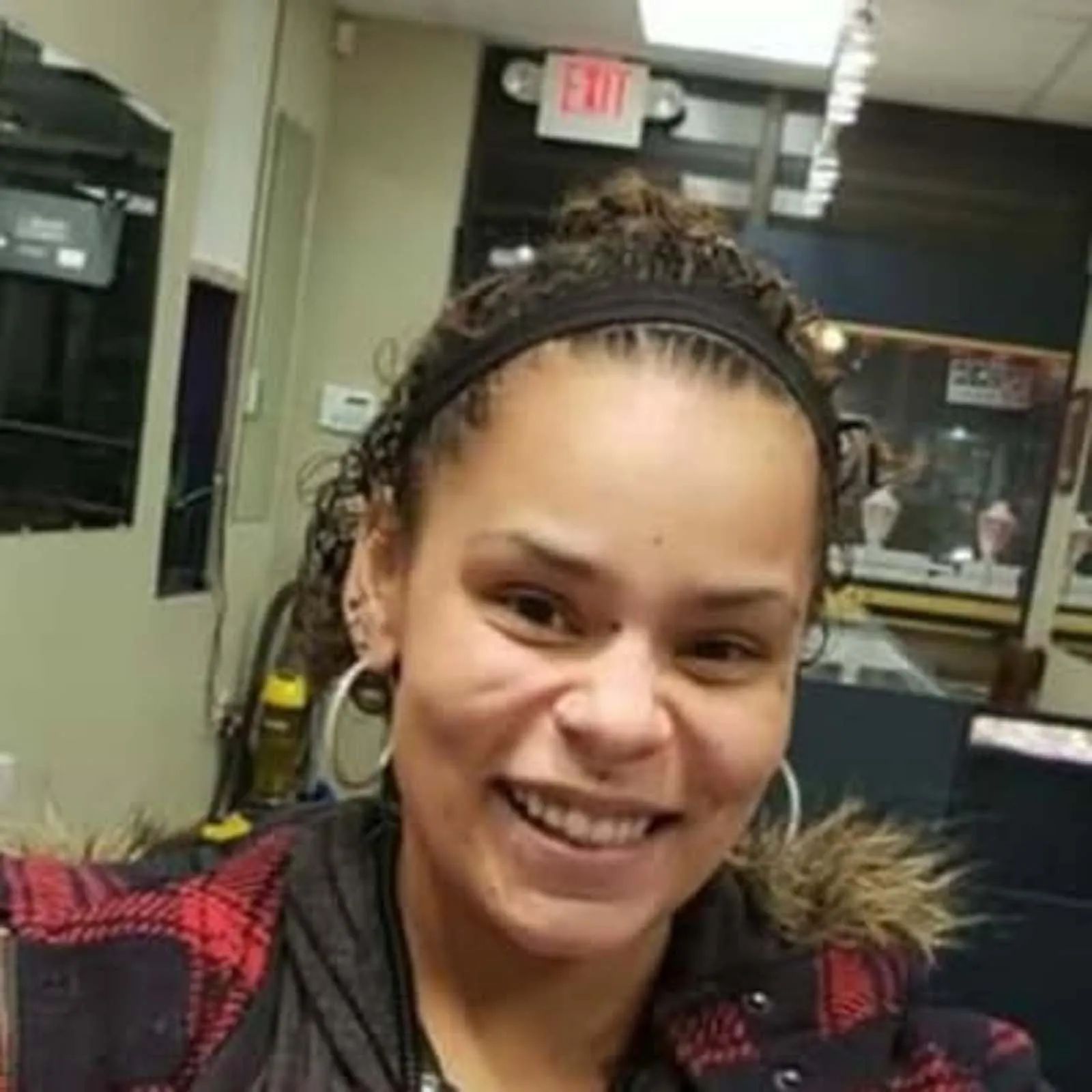 A woman wearing a headband and earrings is smiling in a room.
