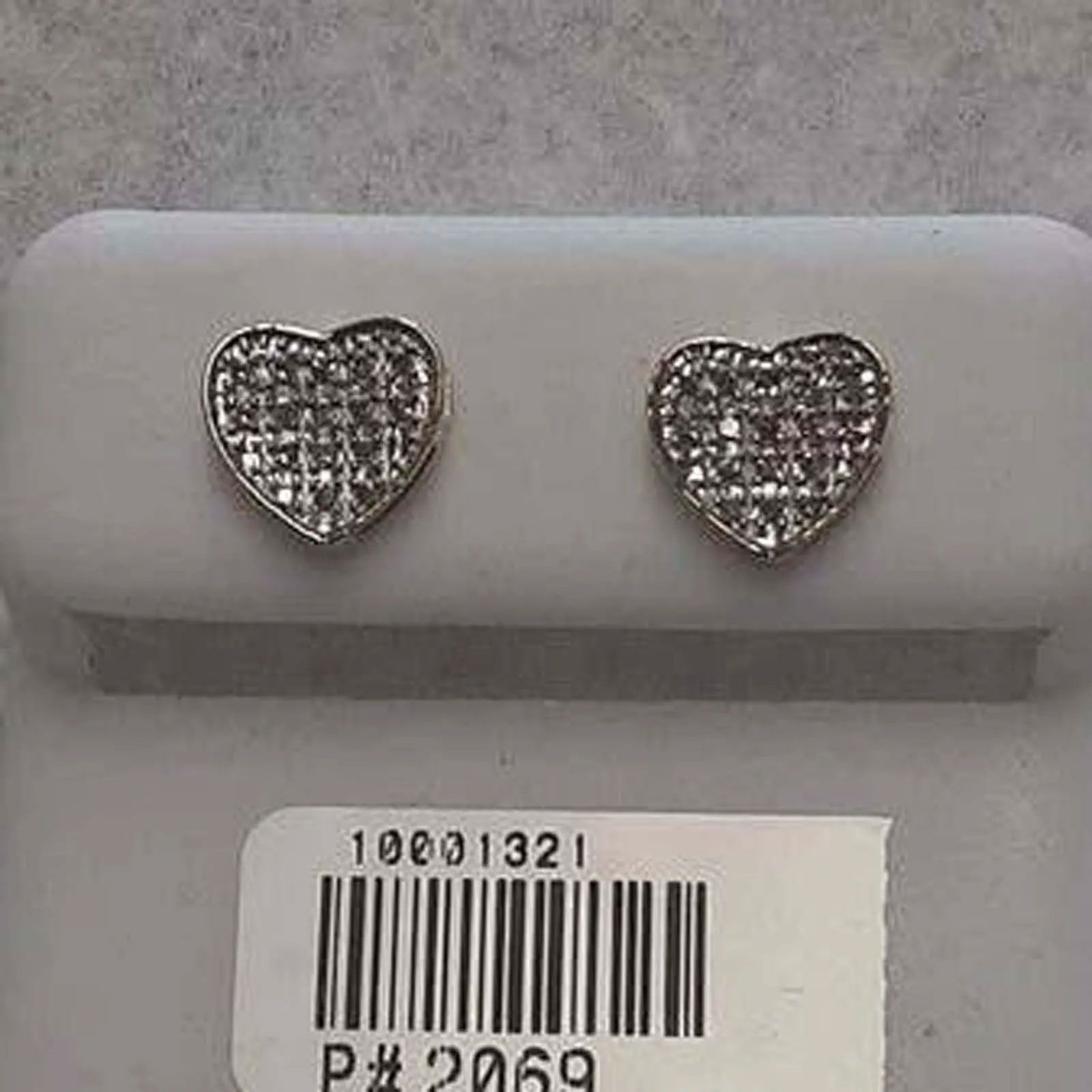 A pair of heart shaped stud earrings in a box with a barcode.