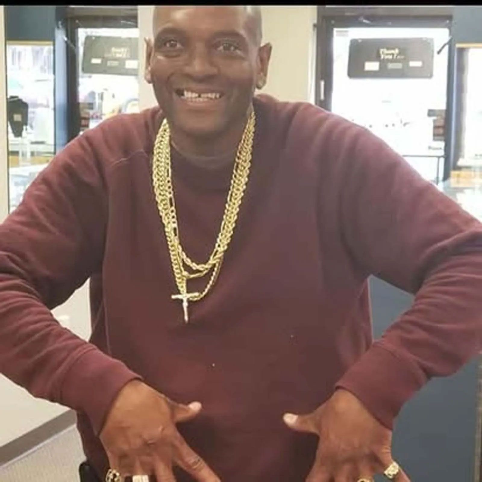 A man wearing a maroon sweater and a gold chain around his neck