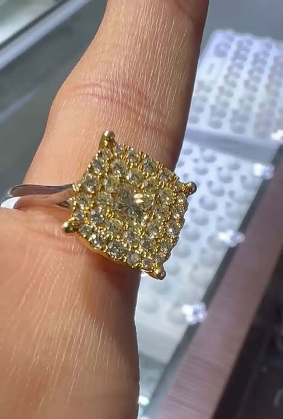 A person is wearing a square shaped ring on their finger
