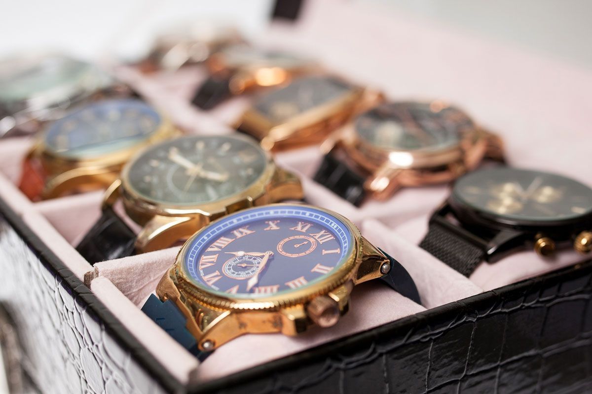 A box filled with watches including a gold watch with roman numerals