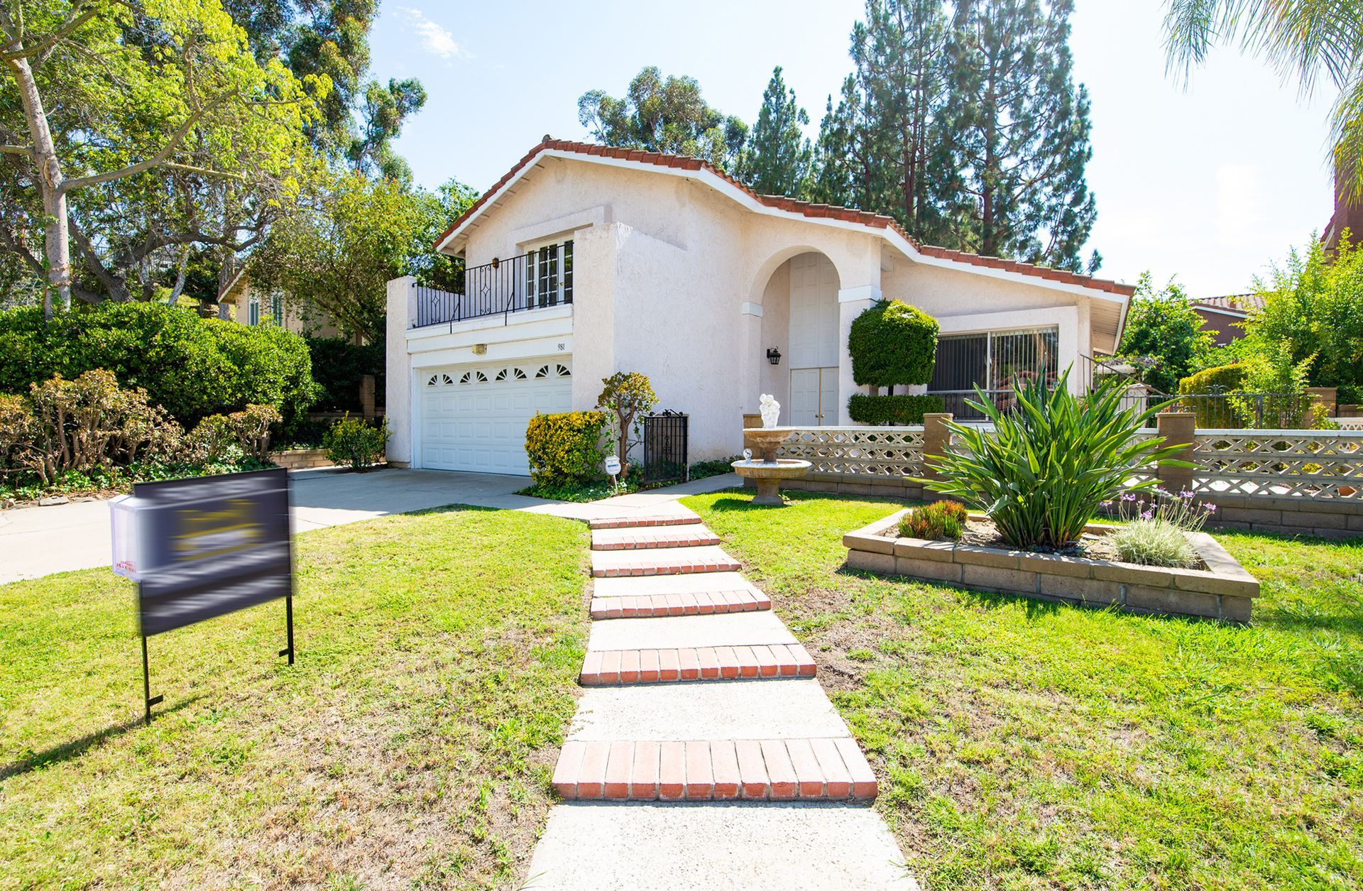 Single-story white house with a stone walkway, green lawn, and trees in the front yard