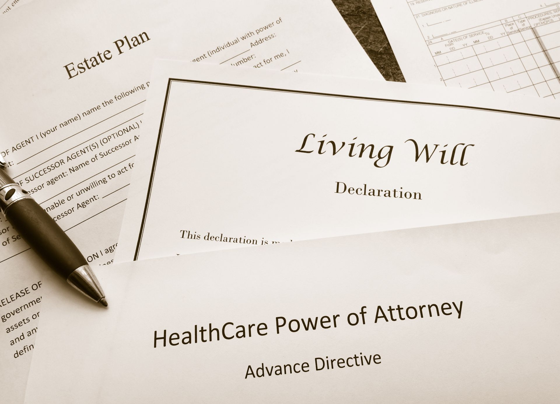 Living will and healthcare power of attorney forms beside a pen on a desk