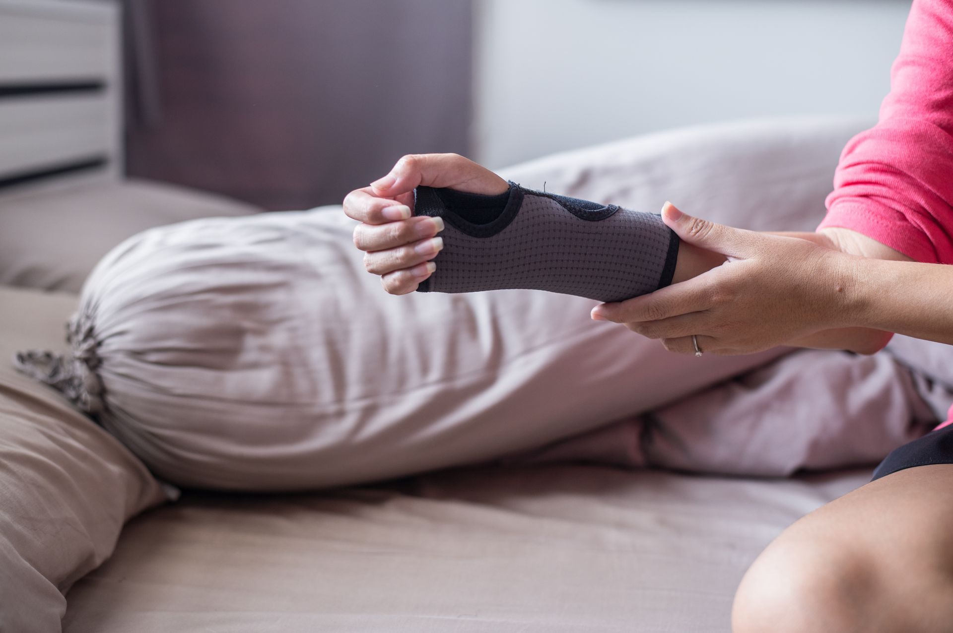 Person putting on a wrist brace while seated on a bed