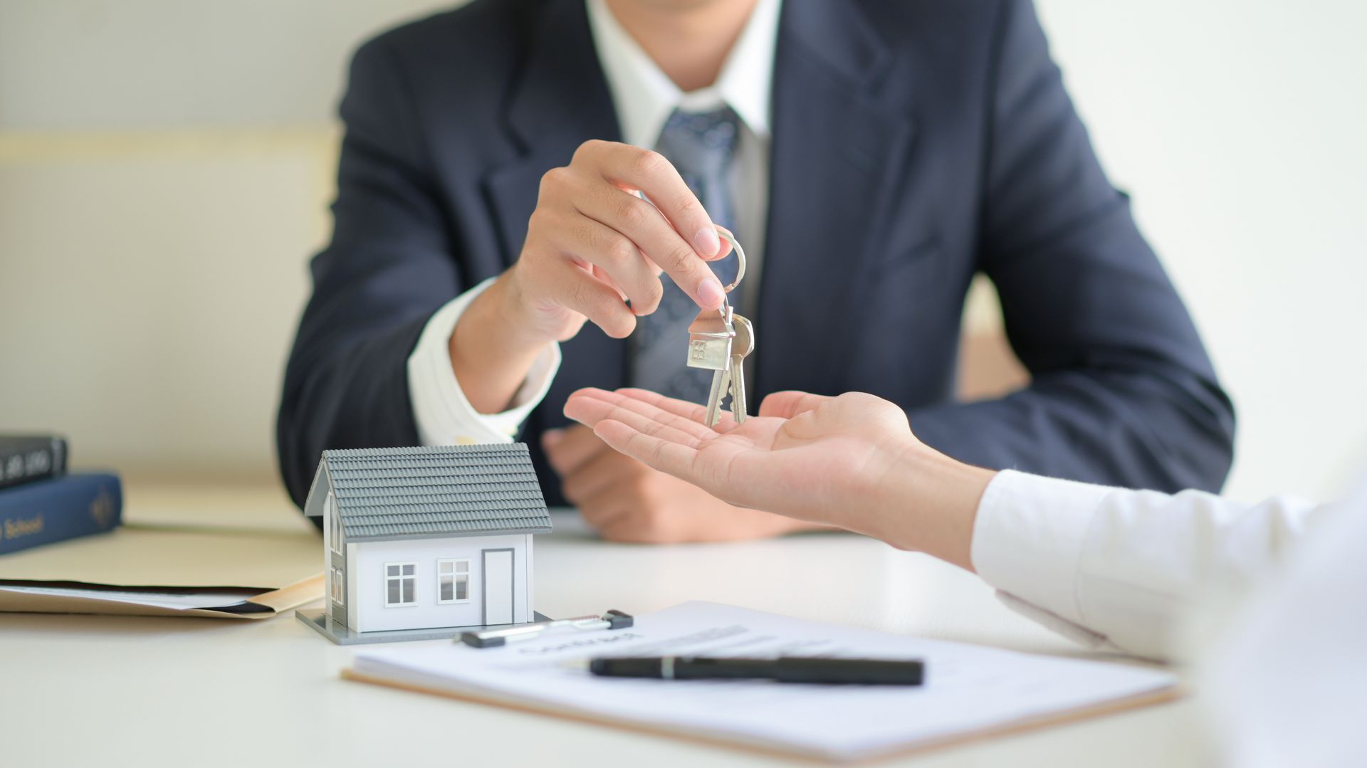 Handing over house keys across a desk during a real estate signing meeting
