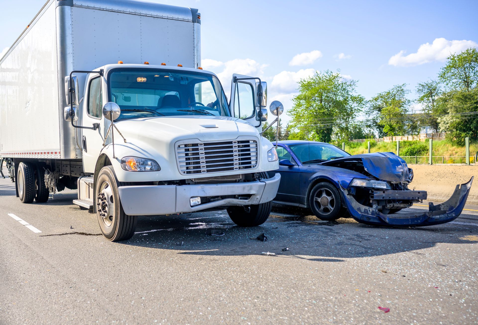 White box truck and damaged black car after a collision on a sunny road