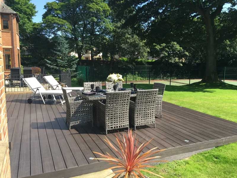 A large decked area with garden furniture and sun lounders on it.