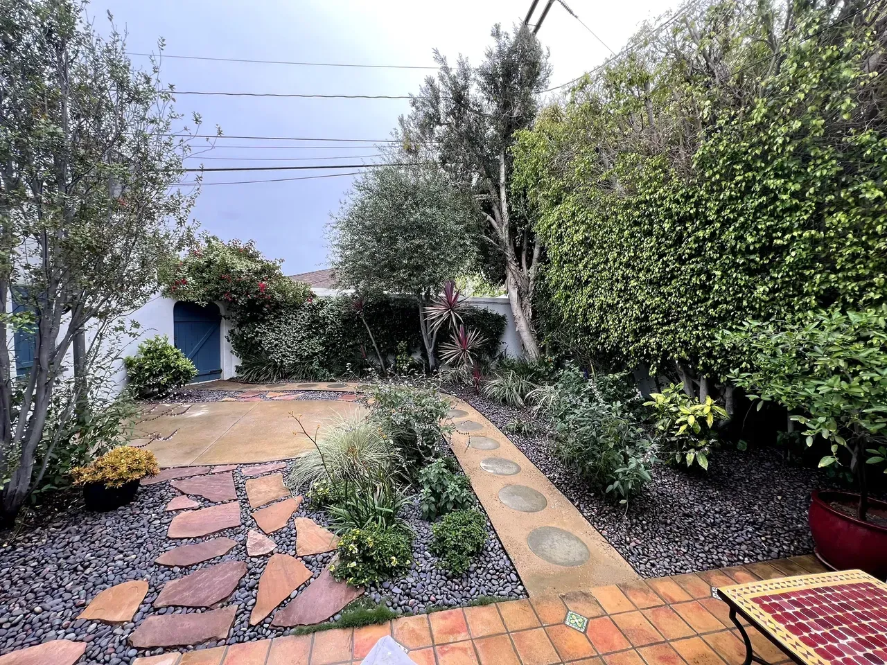 Garden path with patterned stone pavers, green hedges, and a small building in the background