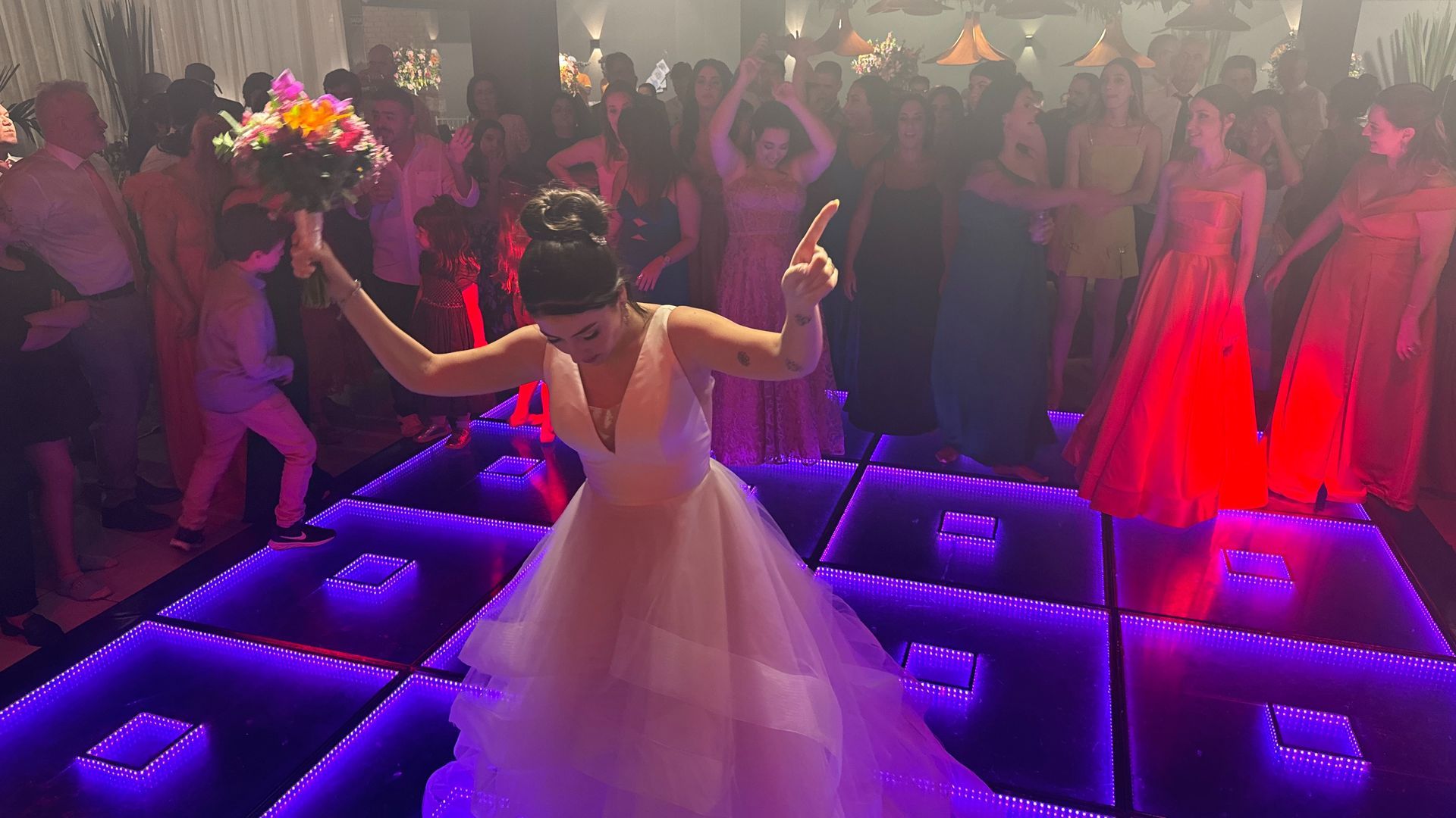 Uma noiva está segurando um buquê de flores enquanto dança na pista de dança.