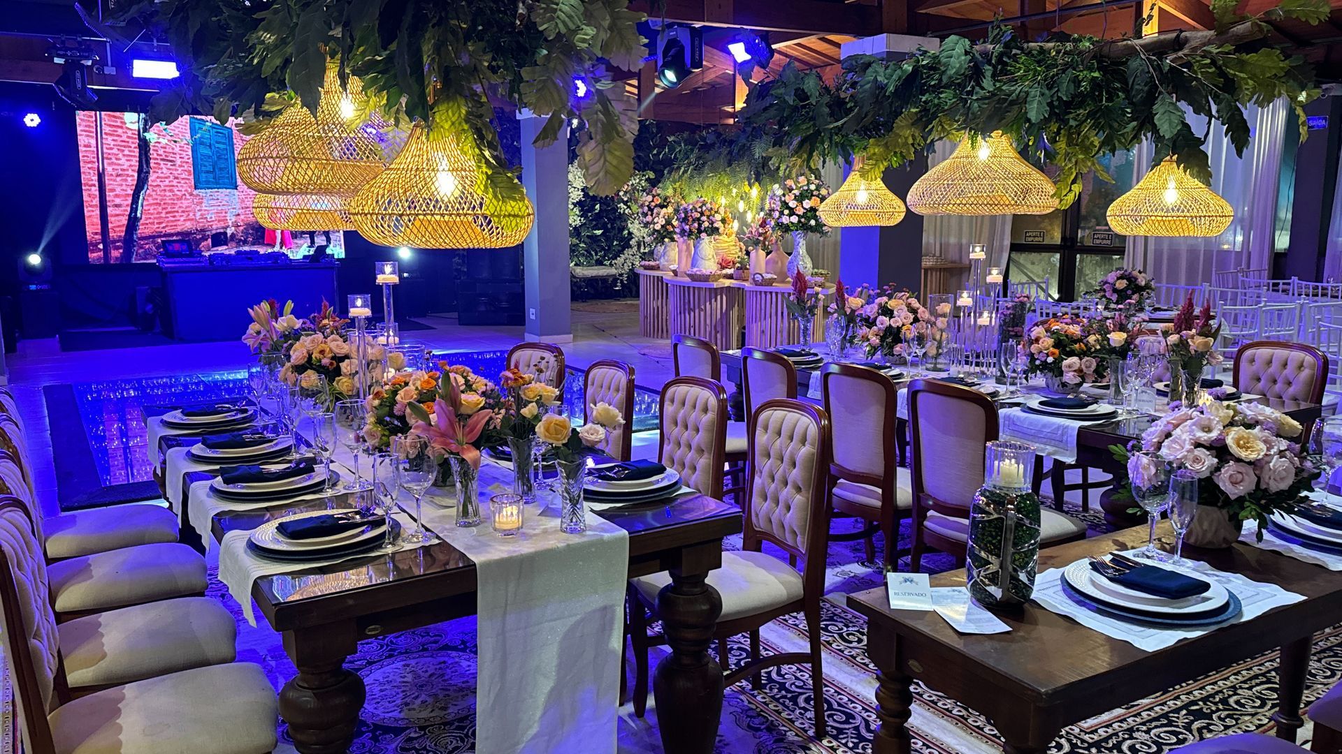 Uma grande sala com mesas e cadeiras preparadas para uma recepção de casamento.