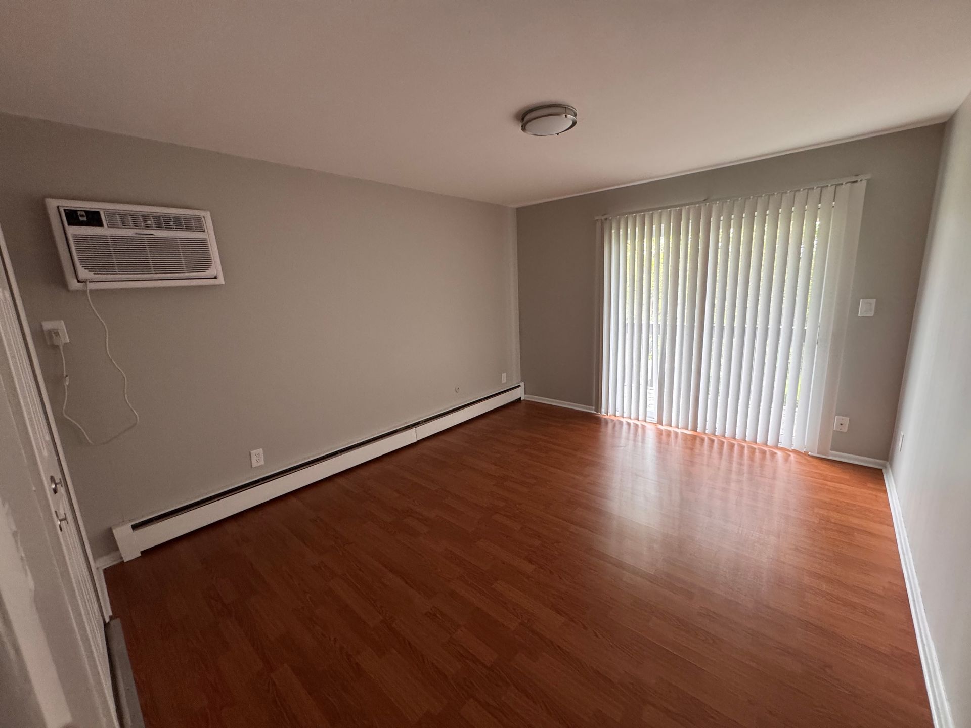 A living room with hardwood floors and a sliding glass door.