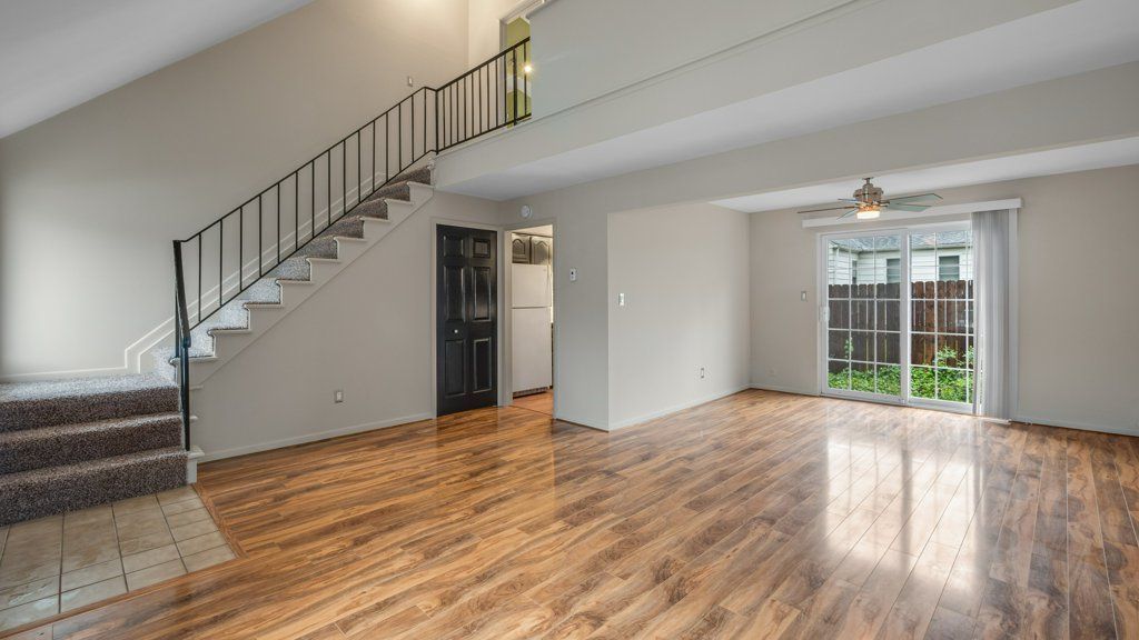 An empty living room with hardwood floors and stairs.