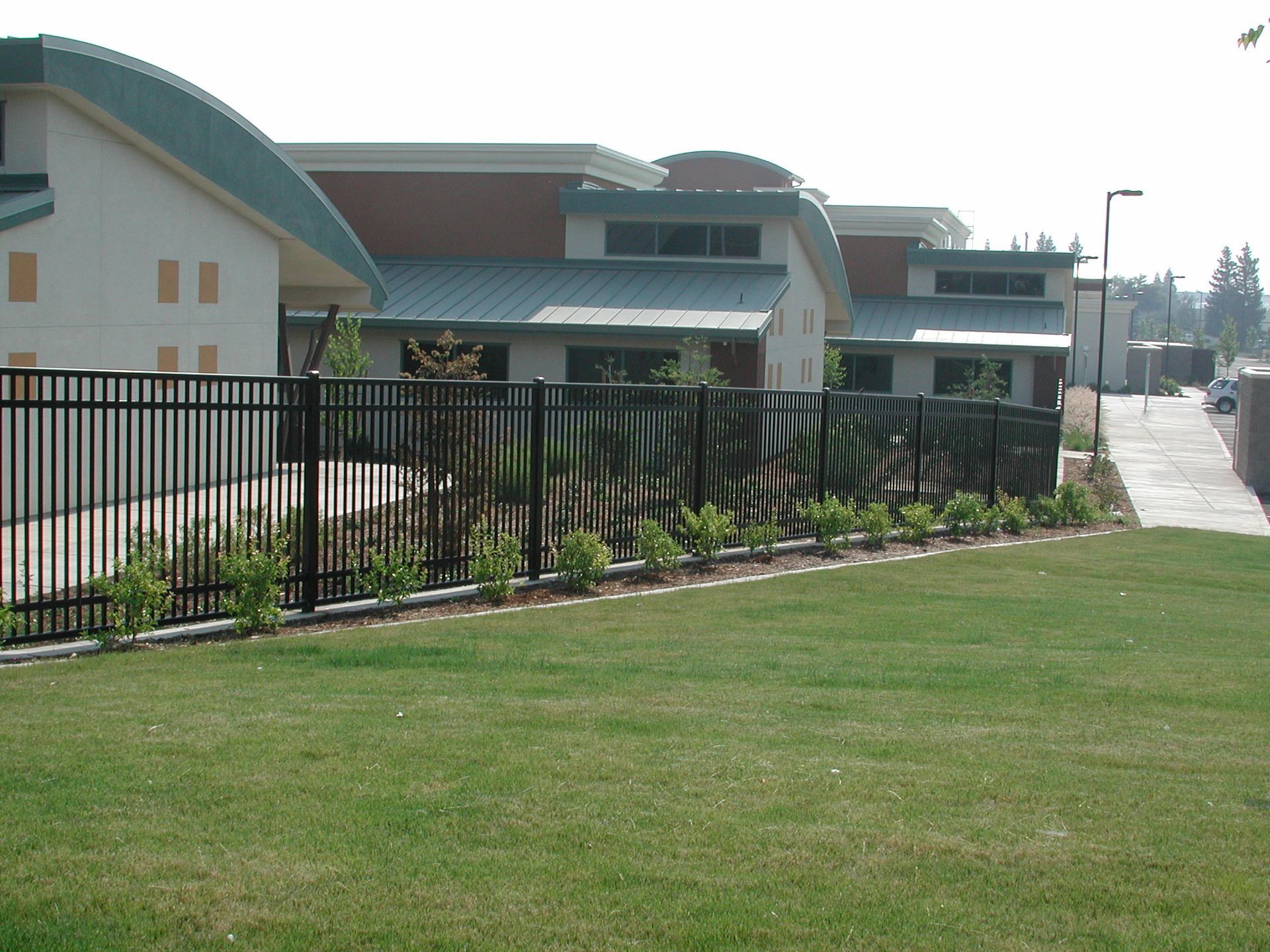 a fence surrounds a lush green field in front of a building