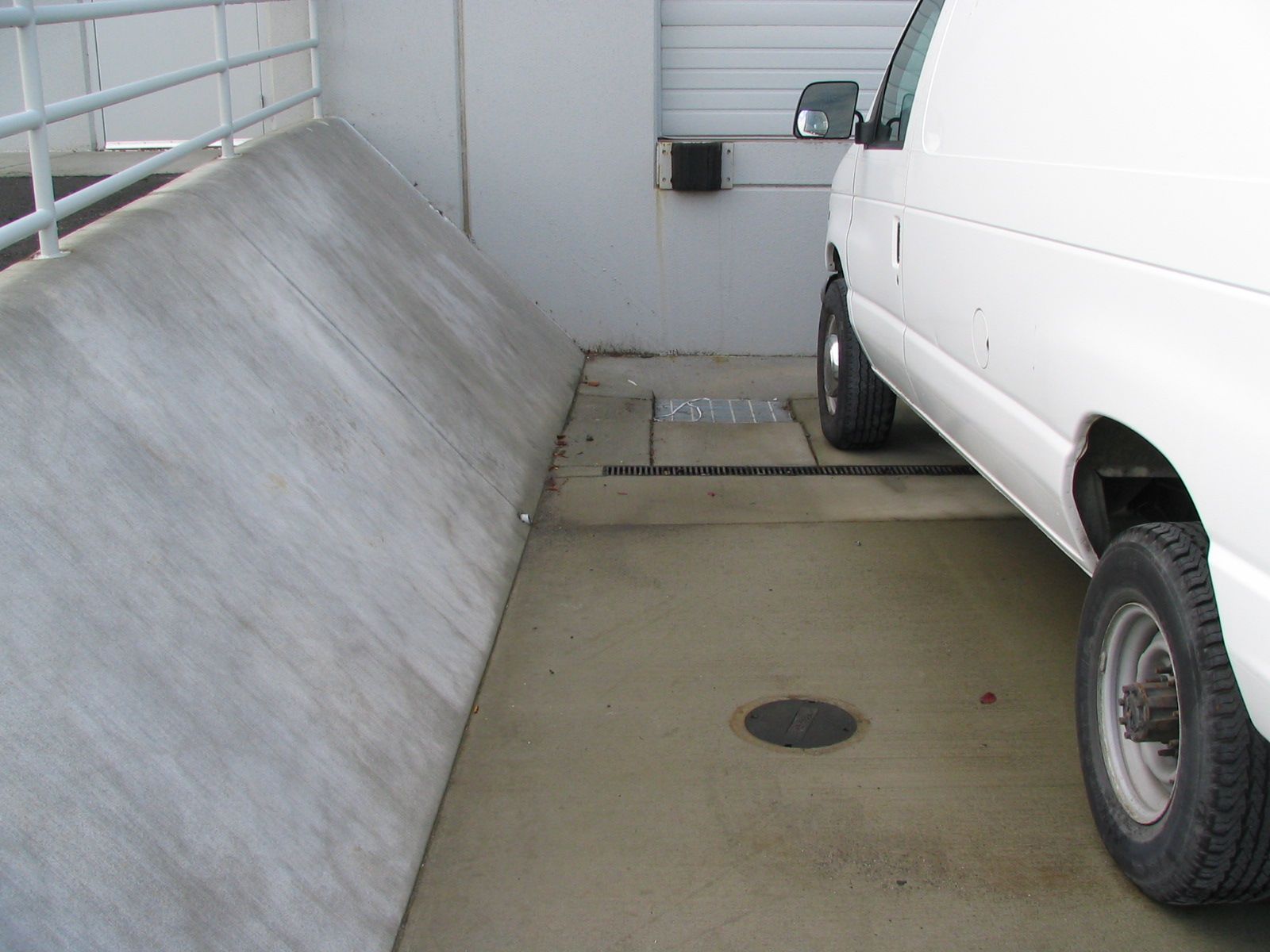 a white van is parked next to a concrete wall